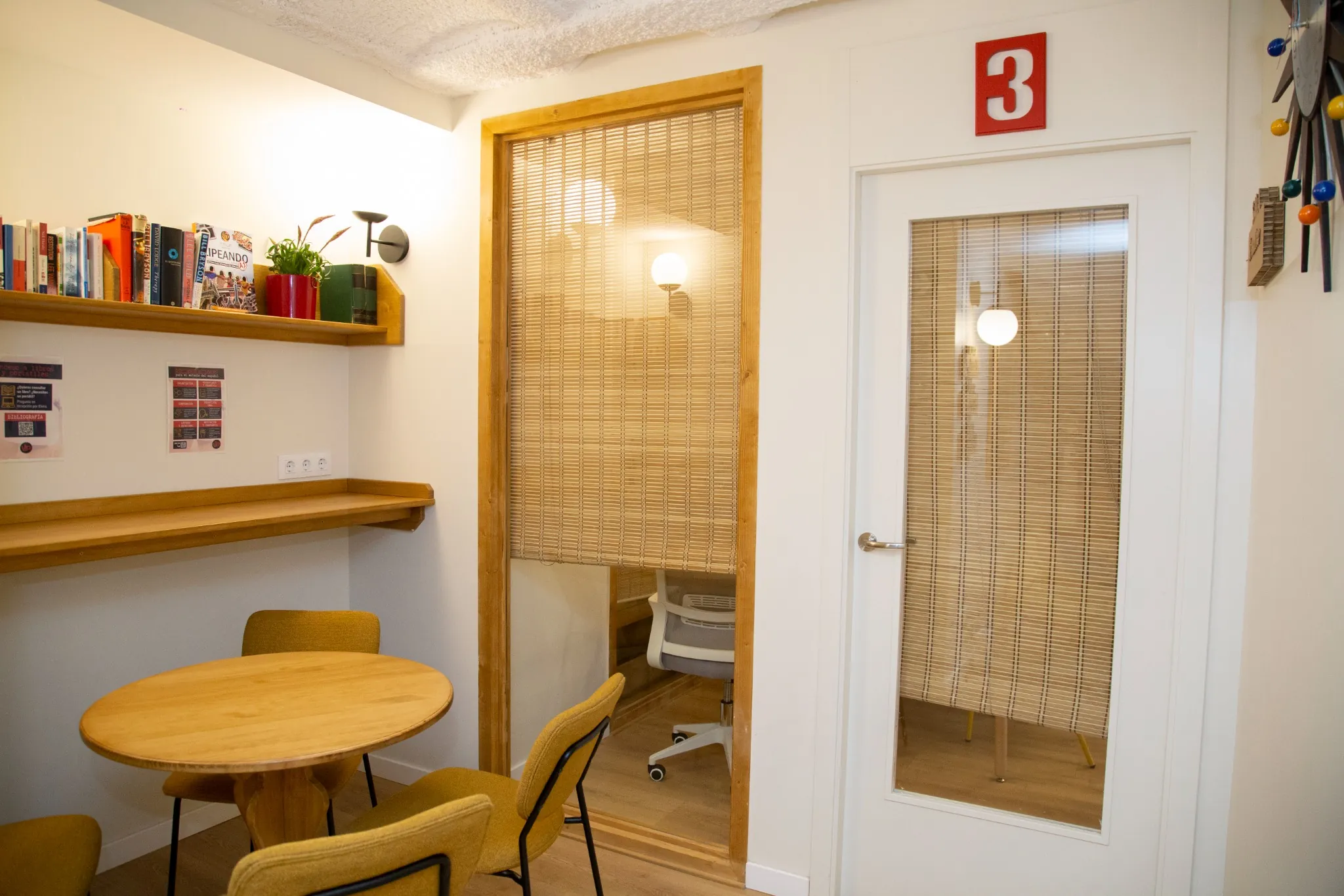 Espacio de lectura y descanso con libros, sillas y mesa redonda en BCNLIP UP en Barcelona.