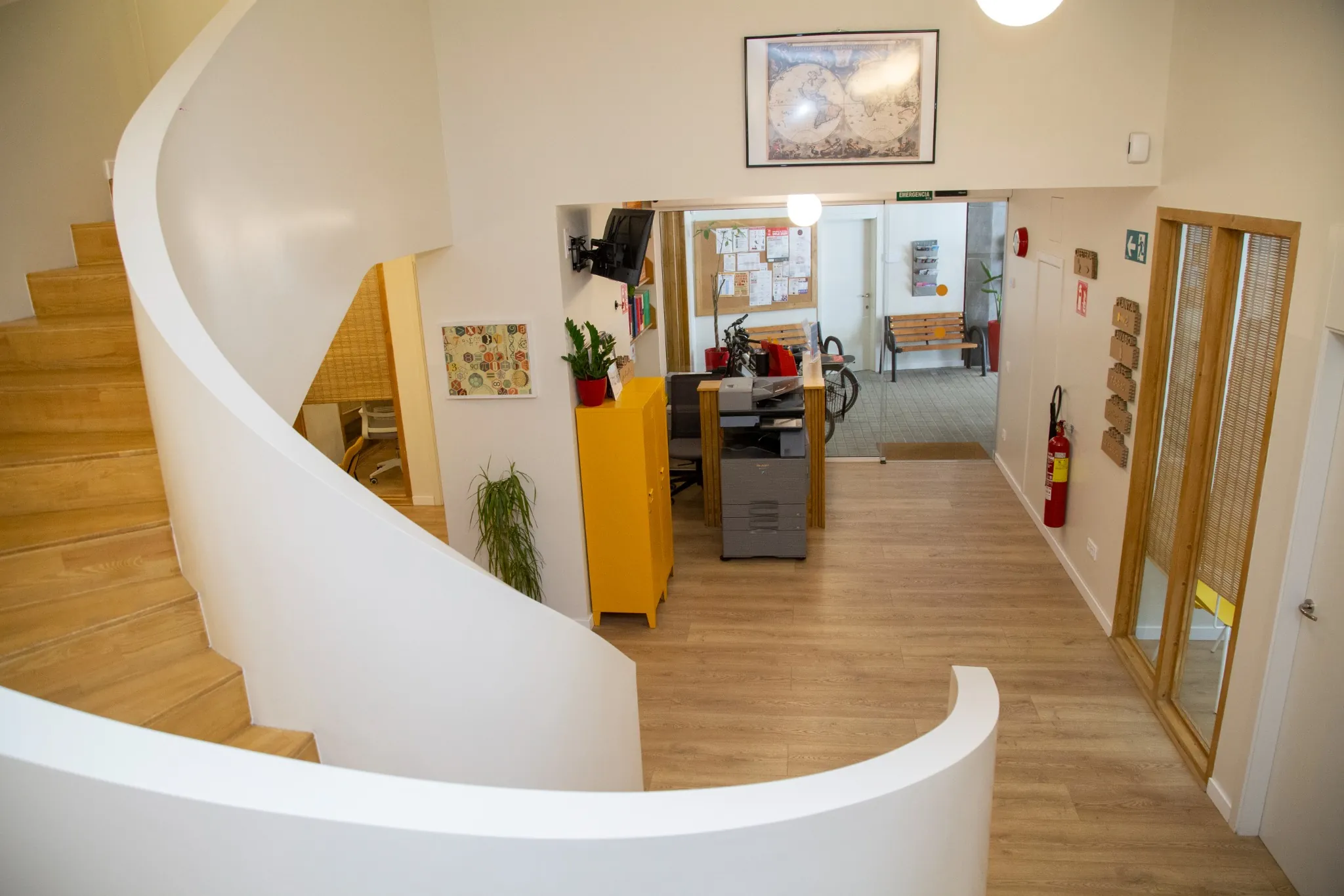Interior moderno de la escuela de idiomas BCNLIP UP en Barcelona, con escalera curva de madera y zona de recepción.