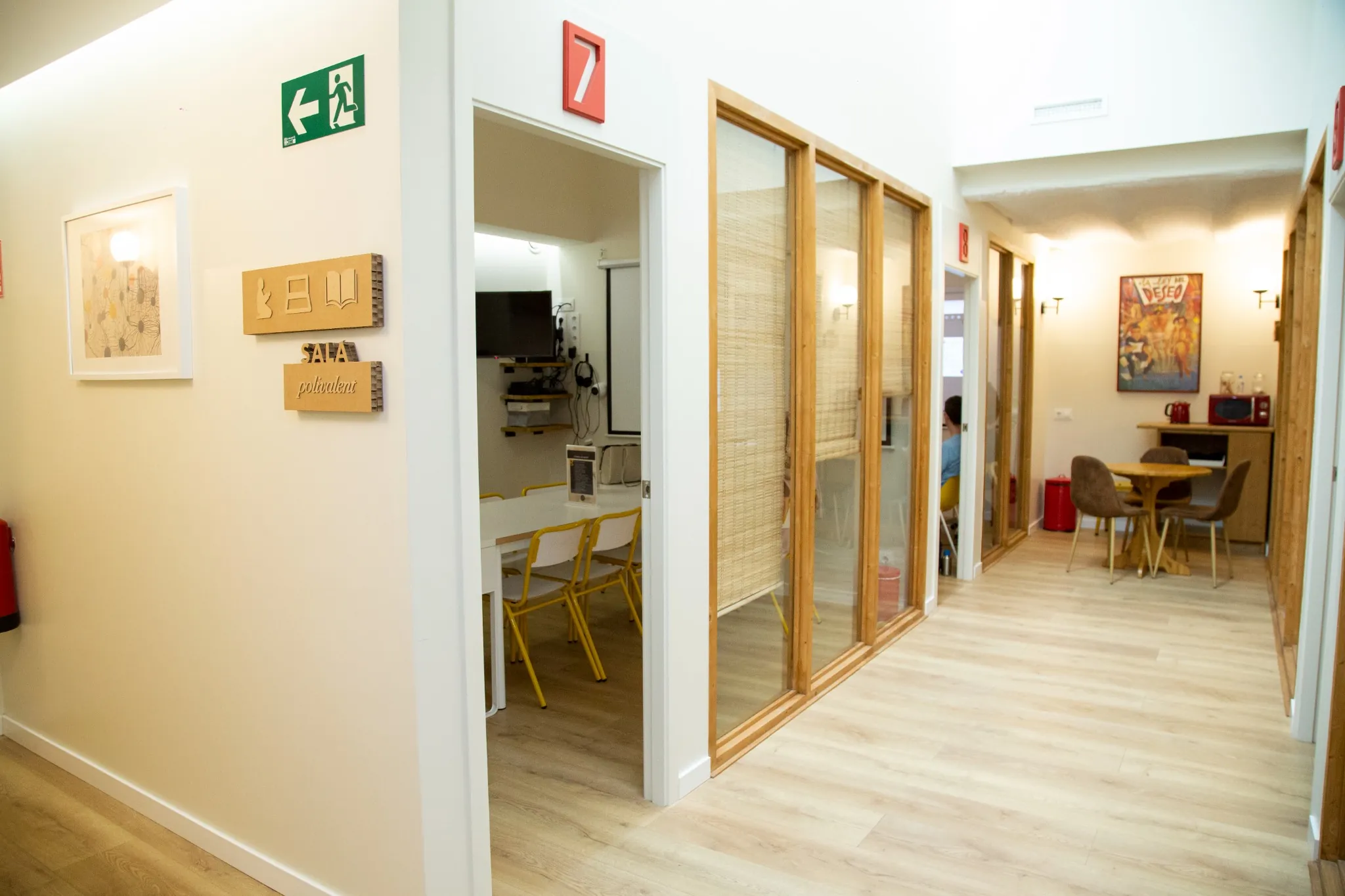 Pasillo luminoso con aulas acristaladas y sala polivalente en la escuela de idiomas BCNLIP UP en Barcelona.